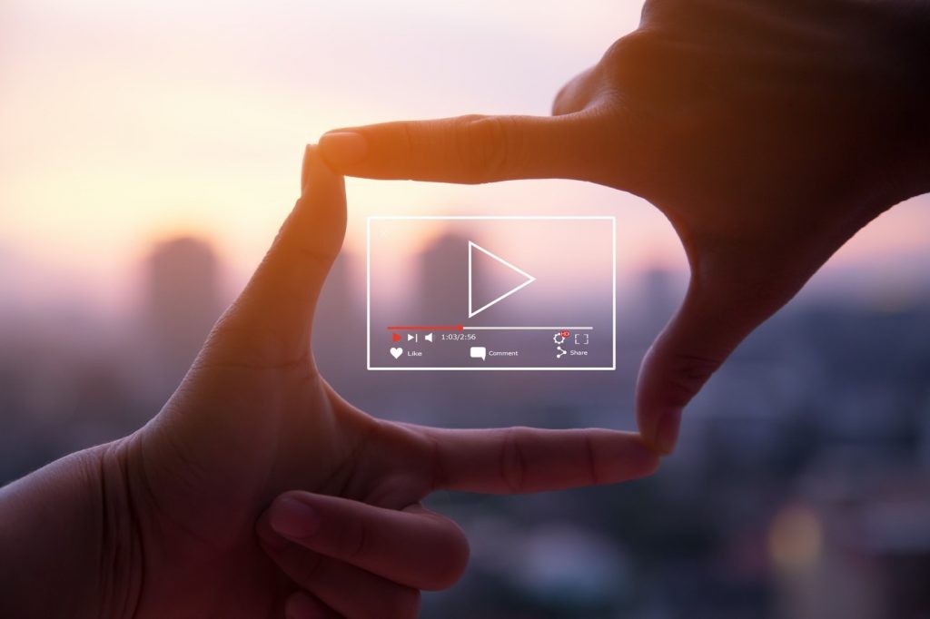 A picture containing person, hand making a square shape and a box with a play button inside it.