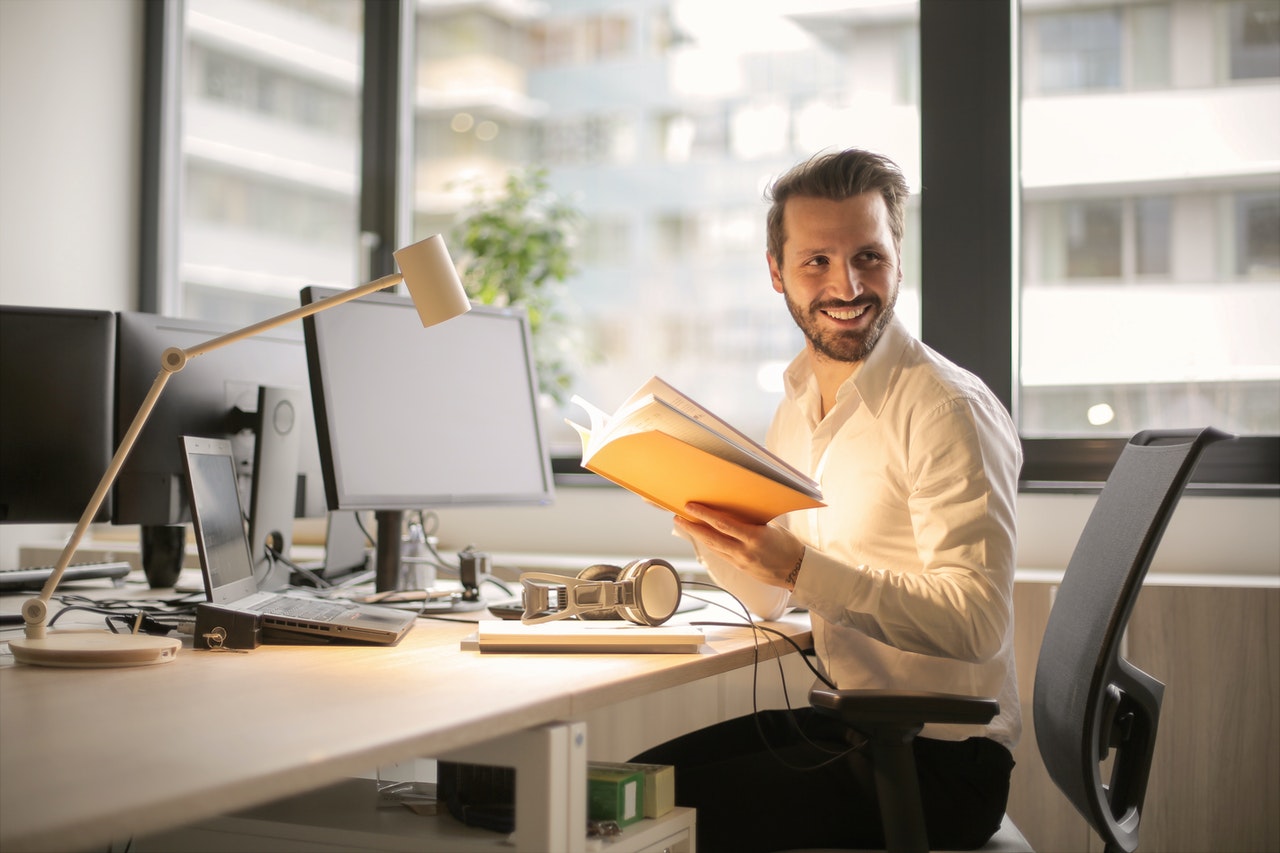 A man smiling while holding a book.